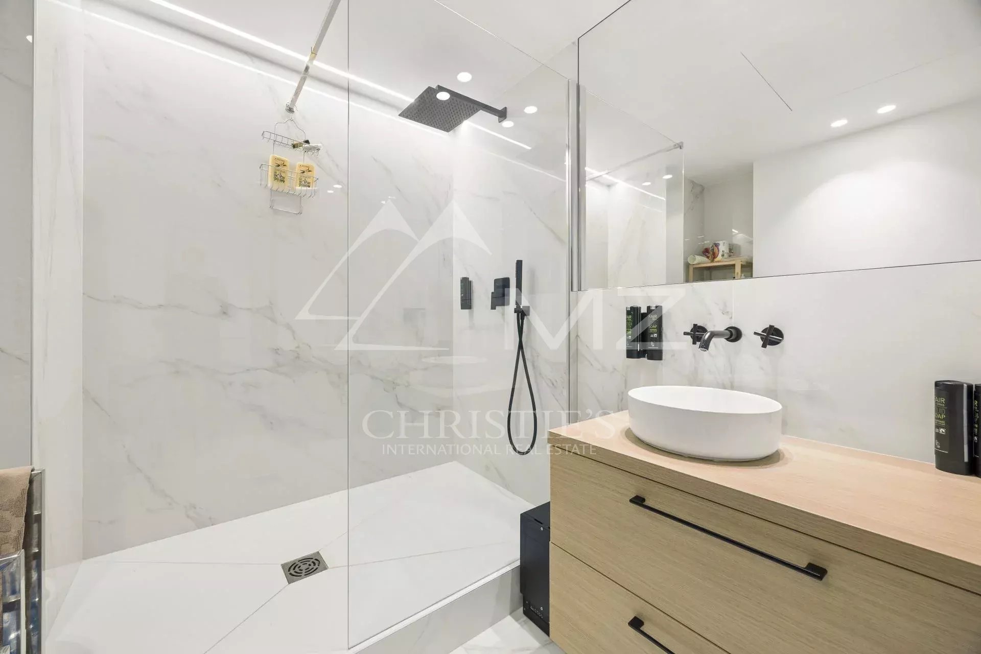 Modern bathroom with glass shower and wooden vanity.