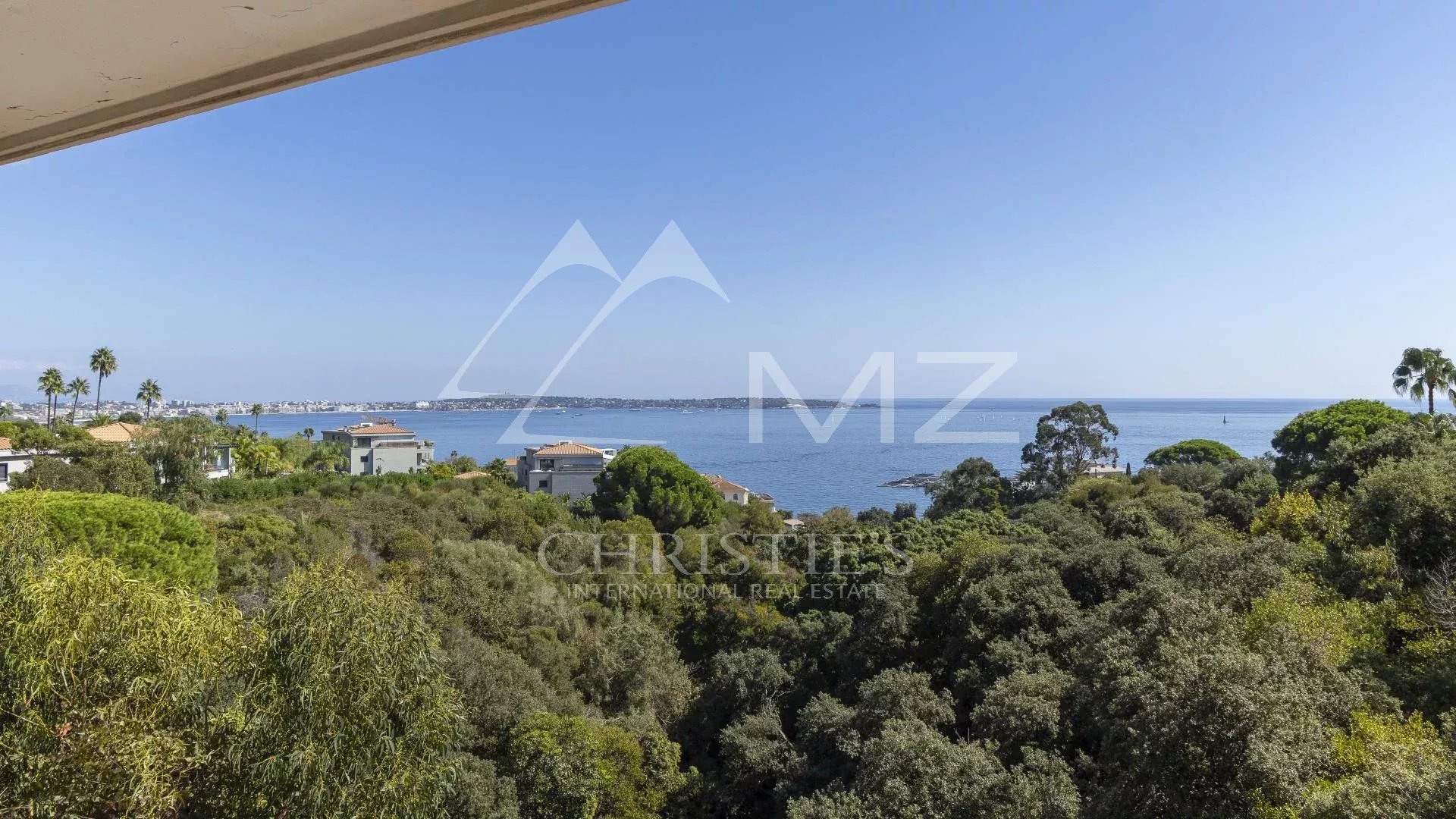 Panoramic sea view from an apartment in Cannes, with trees in the foreground.