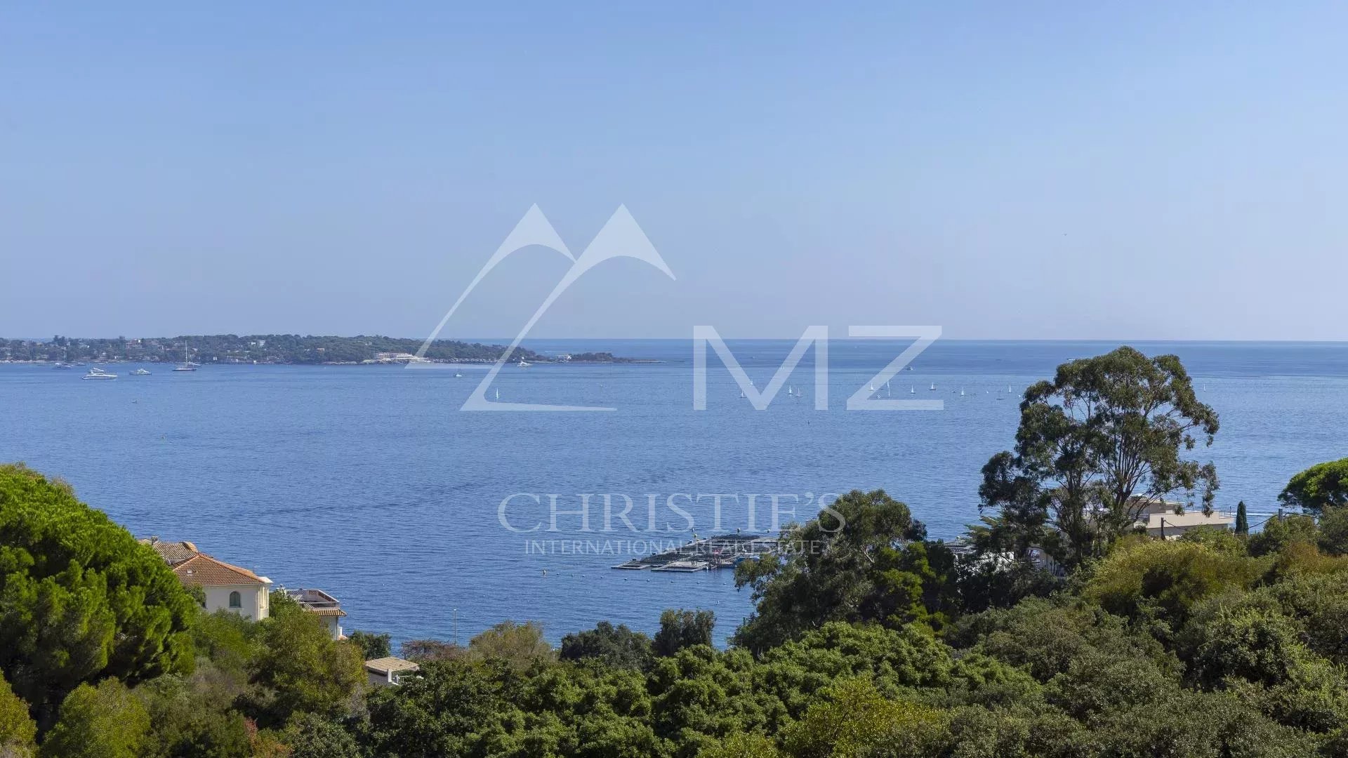 Panoramic sea view from an apartment in Cannes, with trees in the foreground.