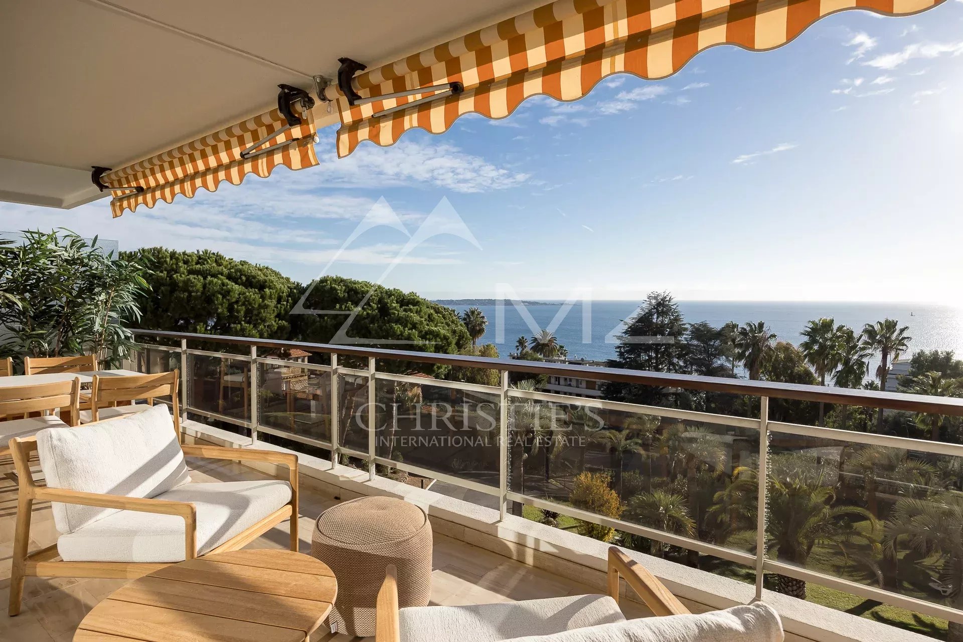 Terrasse avec vue mer à Cannes Terrasse d'un appartement à Cannes avec vue panoramique sur la mer et des sièges en bois.