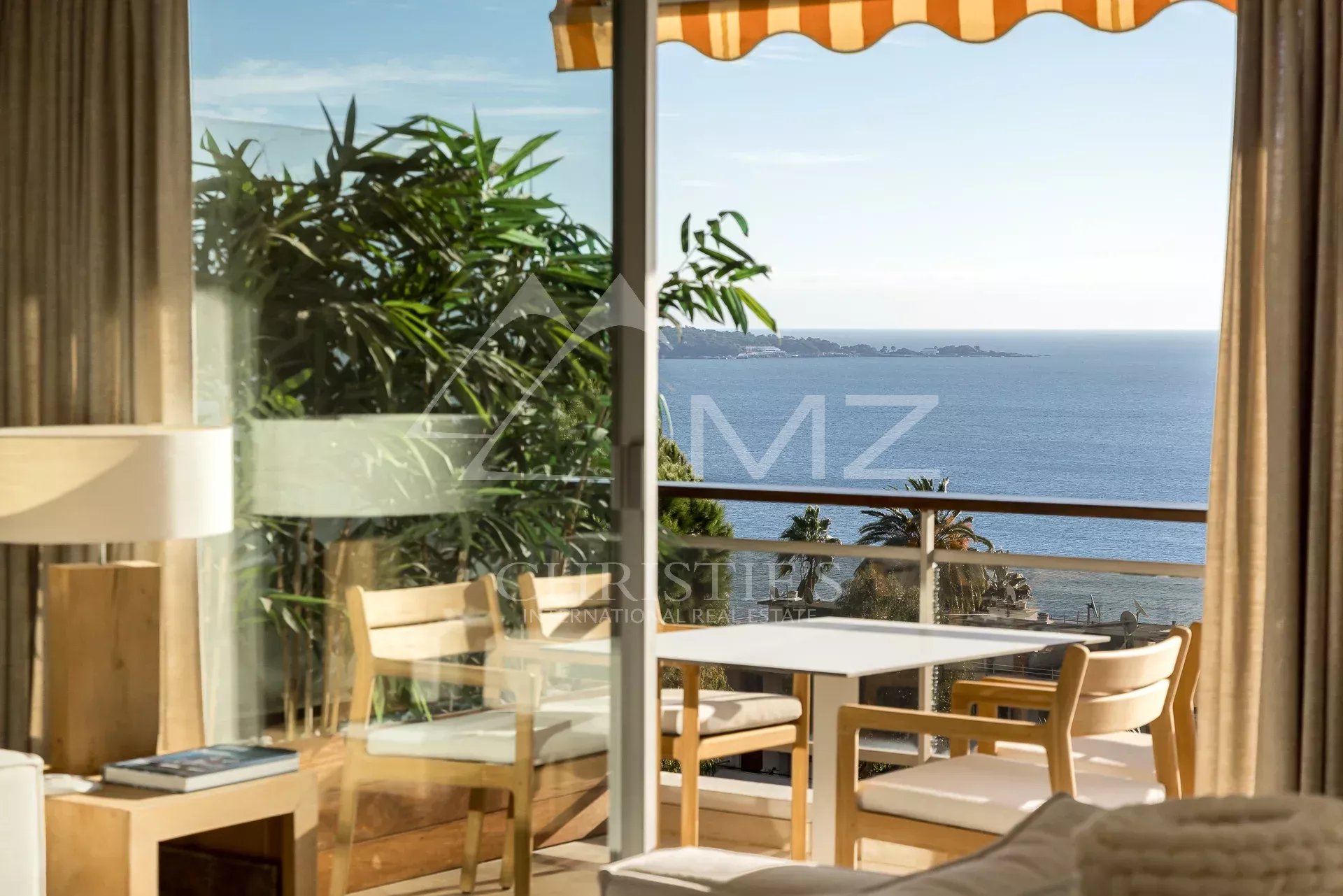 Appartement de prestige à Cannes Intérieur d'un appartement avec vue sur la mer à Cannes, fenêtres ouvertes sur un balcon.