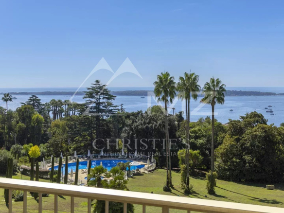 Vue panoramique depuis un balcon sur la mer et un parc avec piscine à Cannes.