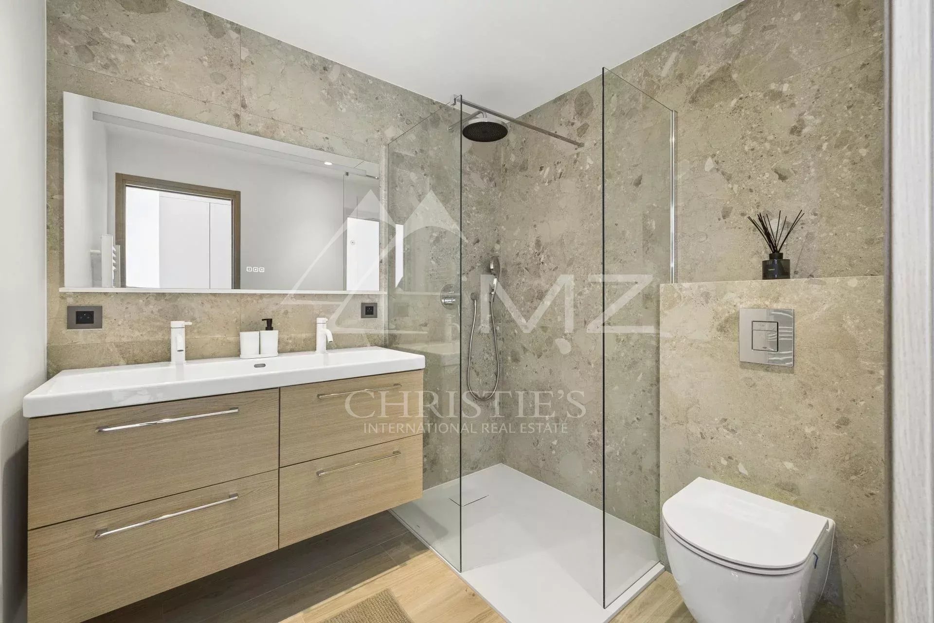 Modern bathroom with glass shower and wooden vanity.