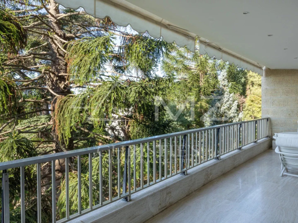 Terrace of a contemporary apartment in Cannes with views of the sea and surrounding greenery.