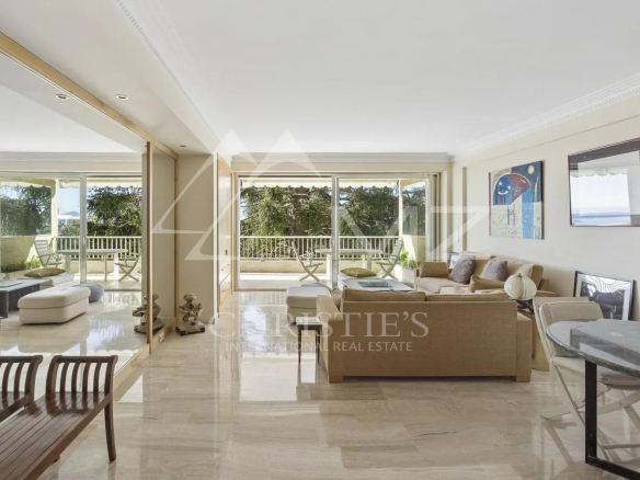 Intérieur d'un appartement contemporain à Cannes avec vue sur la mer, salon lumineux et terrasse.