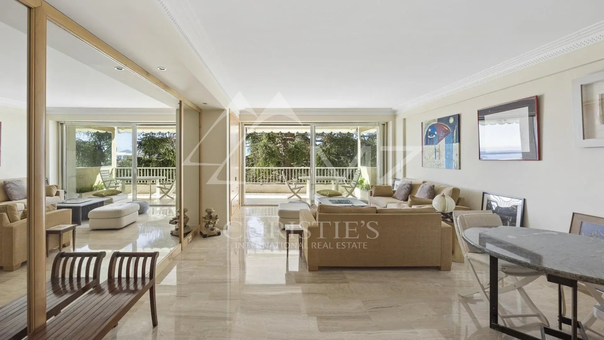 Intérieur d'un appartement contemporain à Cannes avec vue sur la mer, salon lumineux et terrasse.