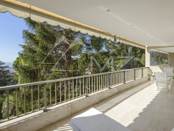 Terrasse d'un appartement contemporain avec vue sur la mer à Cannes, entourée de verdure.