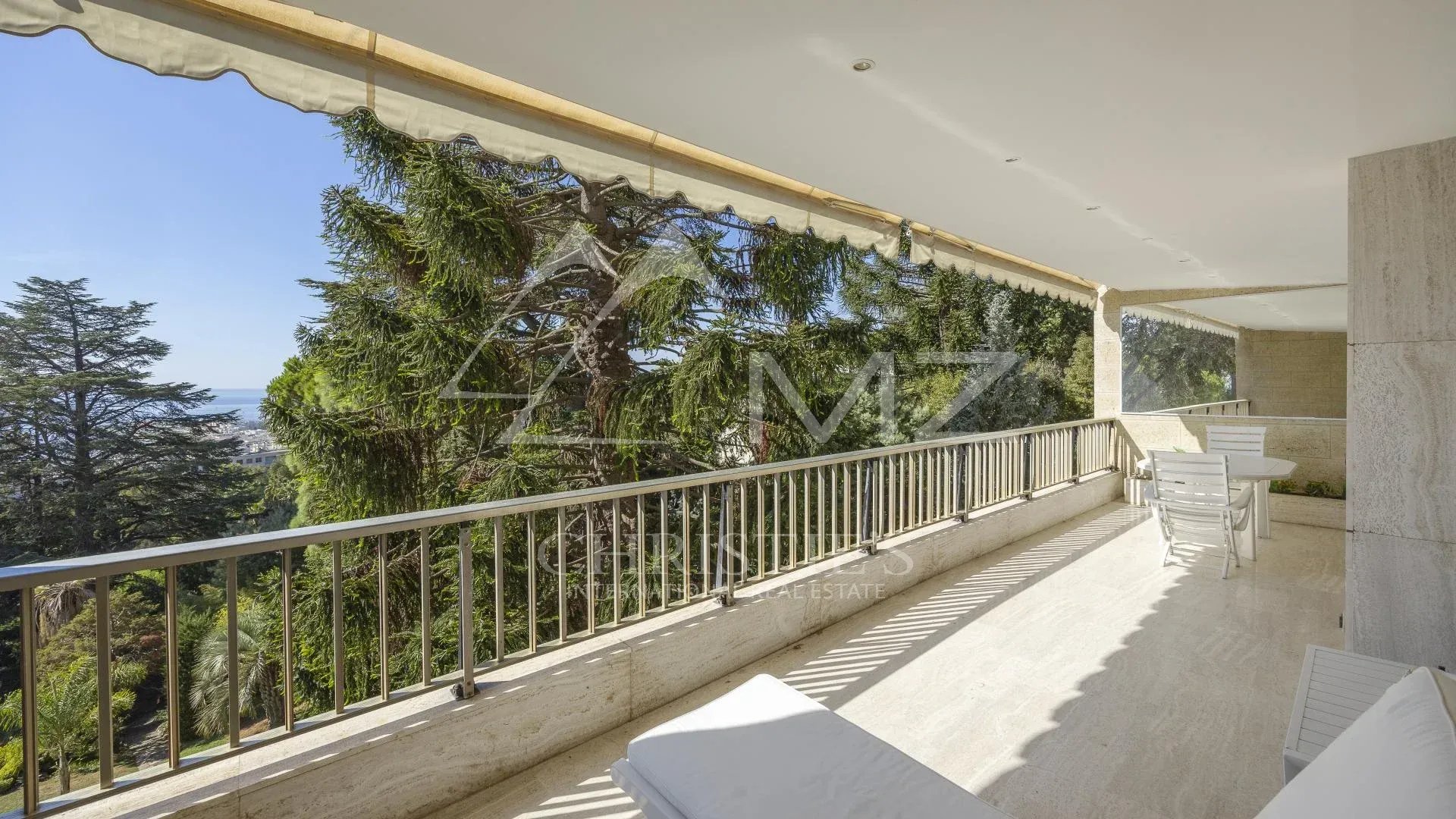 Terrasse d'un appartement contemporain avec vue sur la mer à Cannes, entourée de verdure.