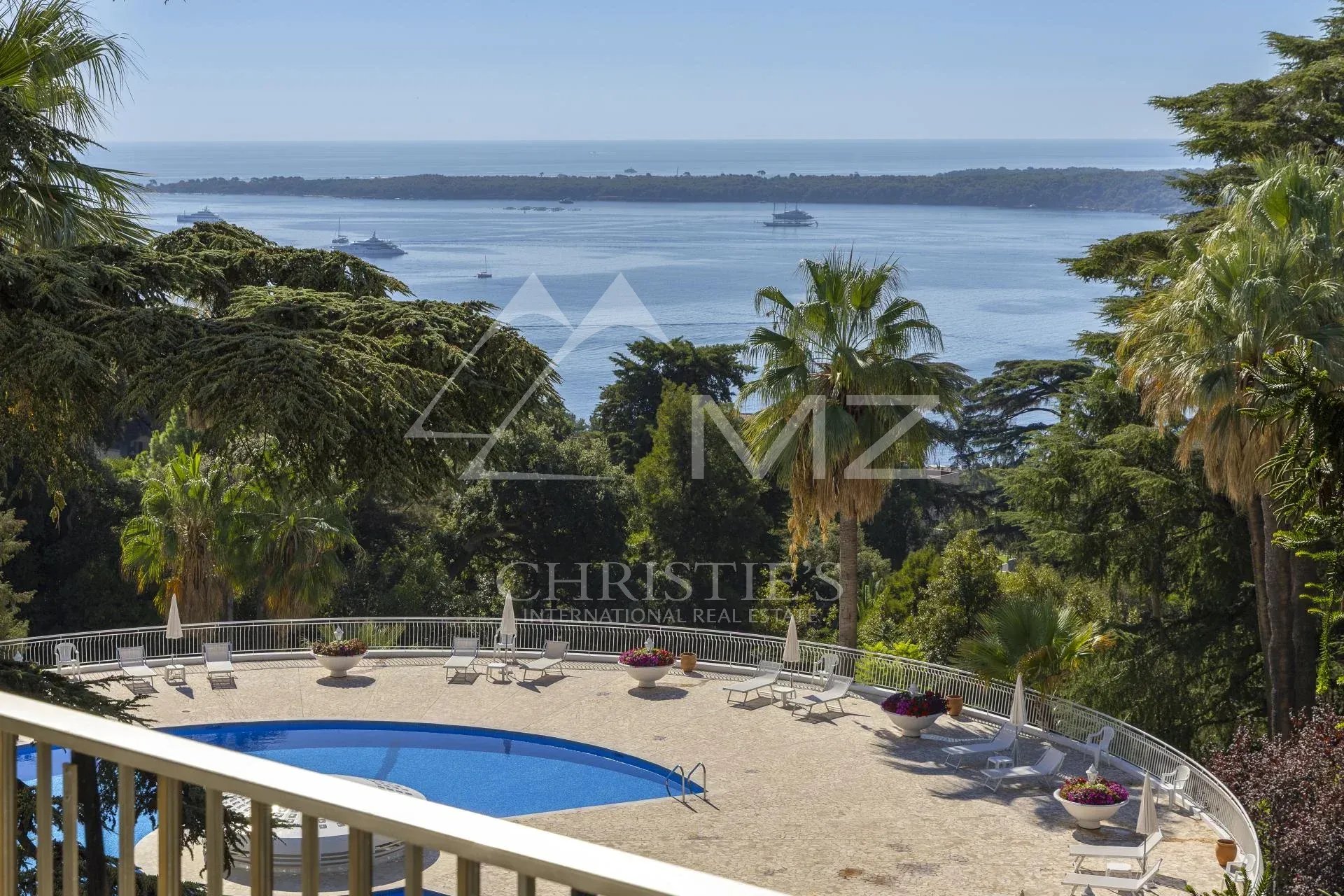 Vue dégagée sur la mer depuis une terrasse avec piscine et palmiers à Cannes.