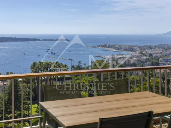 Vue mer depuis un balcon avec table et chaises, surplombant Cannes et les îles de Lérins.