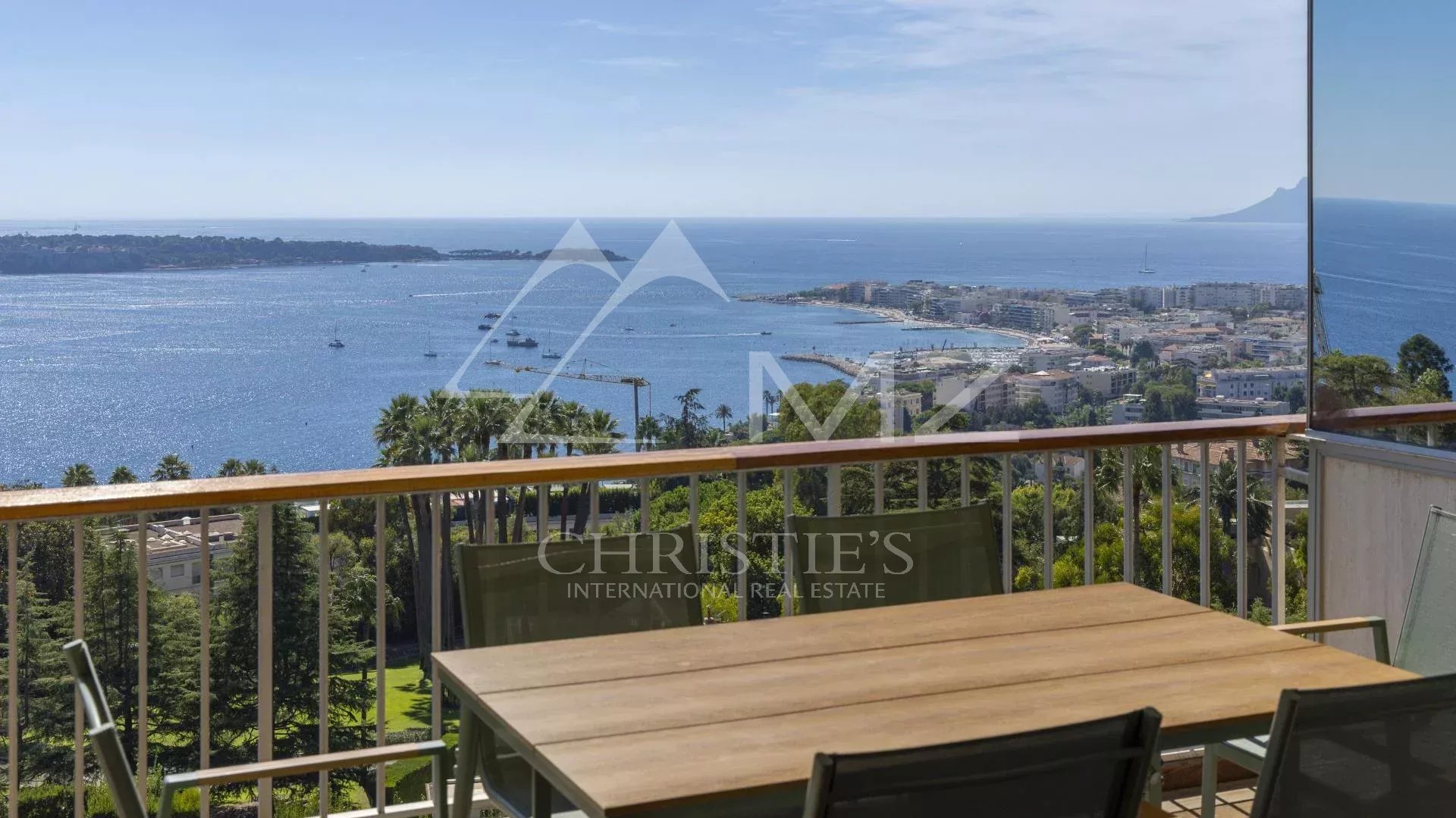 Vue mer à Cannes Vue mer depuis un balcon avec table et chaises, surplombant Cannes et les îles de Lérins.