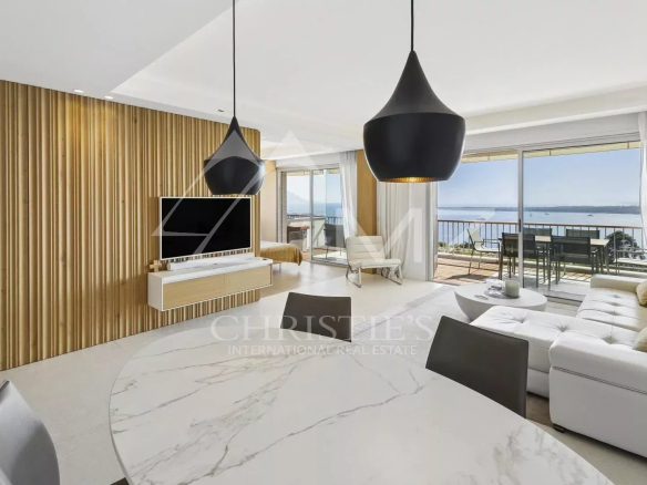 Intérieur d'un appartement contemporain avec vue mer à Cannes, salon lumineux et mobilier moderne.