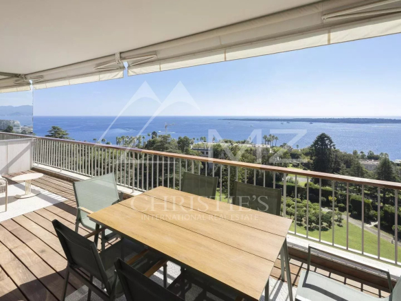 Terrasse d'un appartement contemporain avec vue mer à Cannes, mobilier de jardin en bois et chaises.