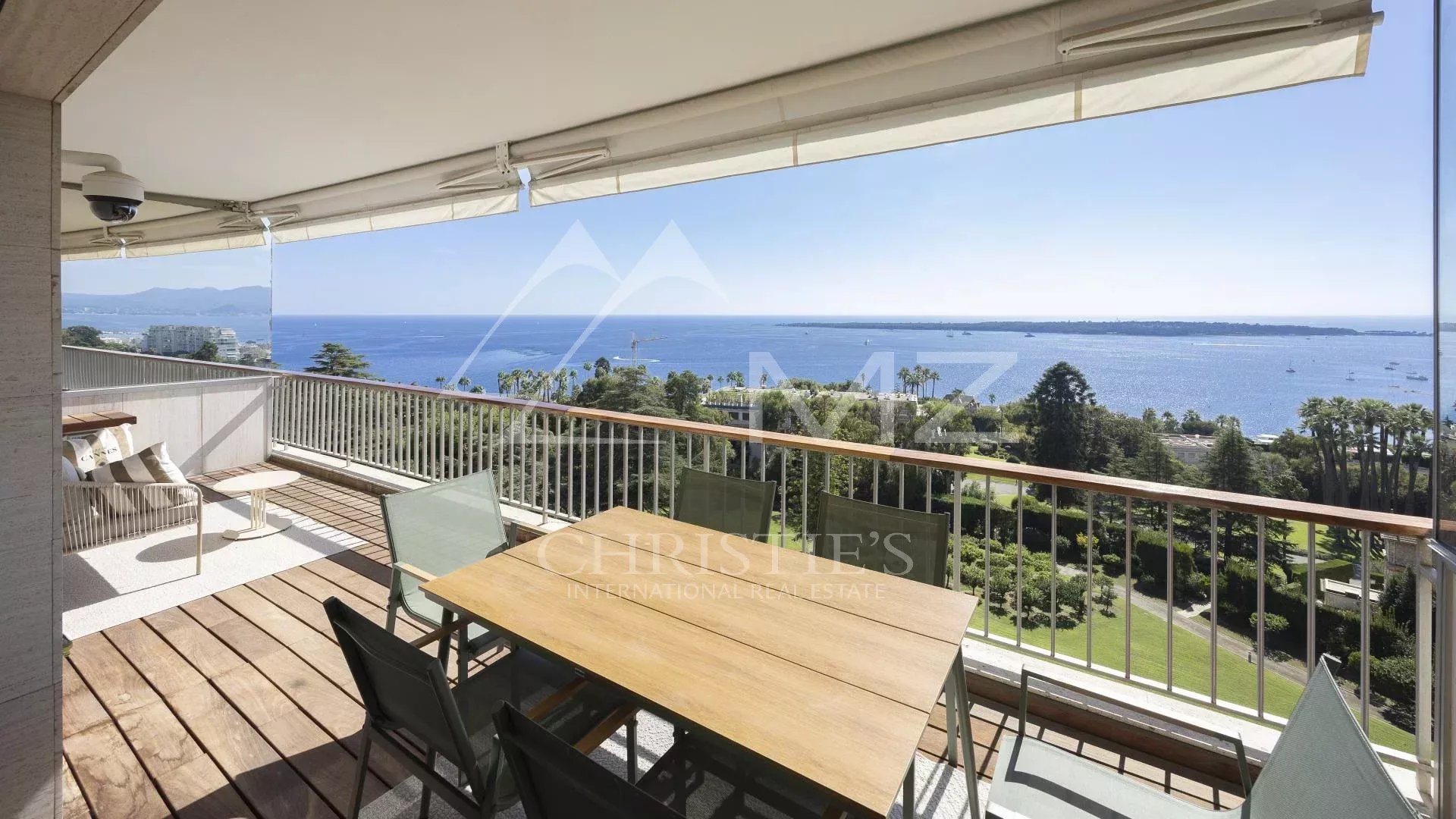 Appartement contemporain avec vue mer à Cannes Terrasse d'un appartement contemporain avec vue mer à Cannes, mobilier de jardin en bois et chaises.