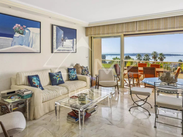 Intérieur d'un appartement à Cannes avec vue sur la mer, salon lumineux et terrasse.
