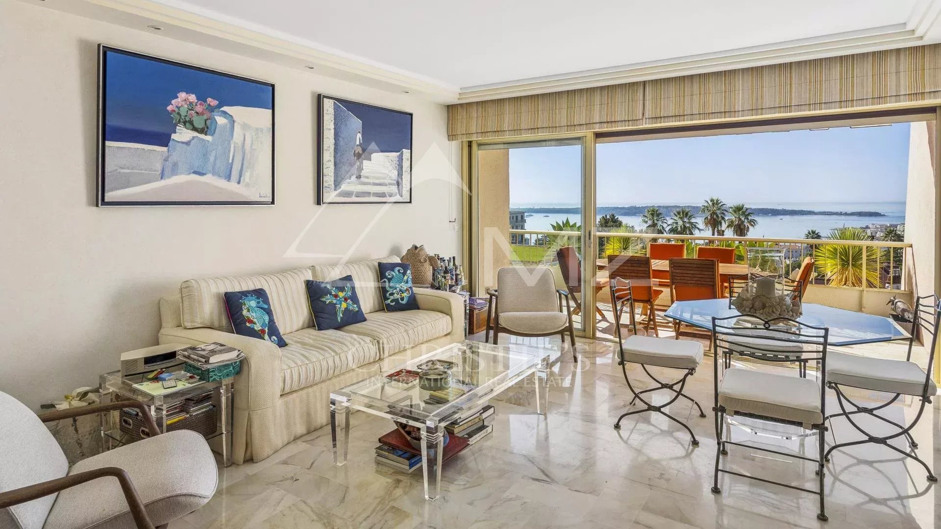 Intérieur d'un appartement à Cannes avec vue sur la mer, salon lumineux et terrasse.