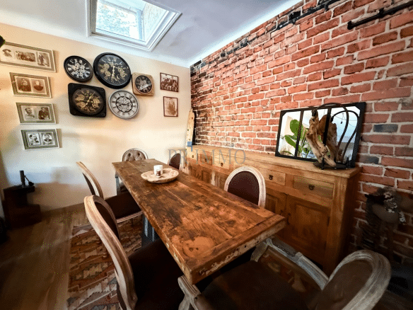 Interior of a house with a wooden table, chairs and exposed brick walls.