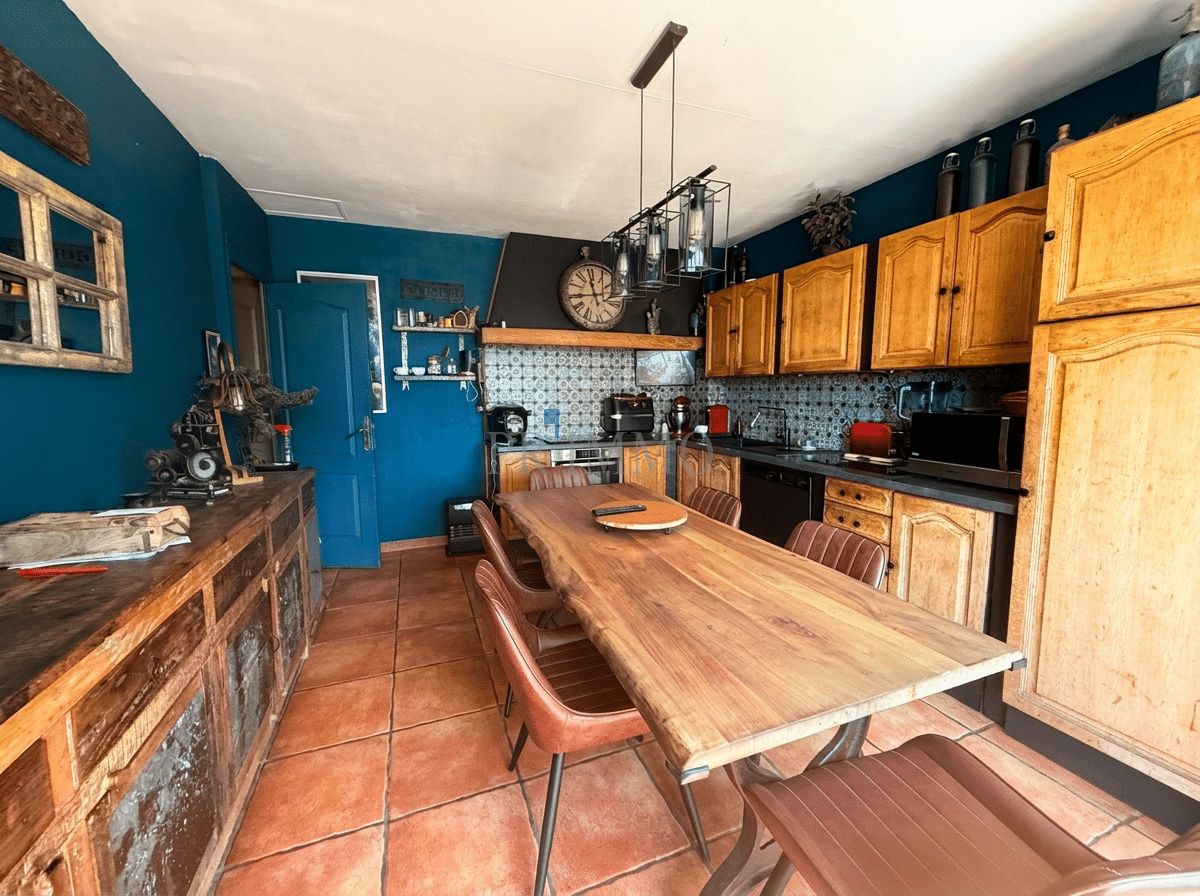 Home kitchen with integrated grocery store Spacious kitchen with wooden table and wooden furniture, dark blue walls, in Roquebrune-sur-Argens.
