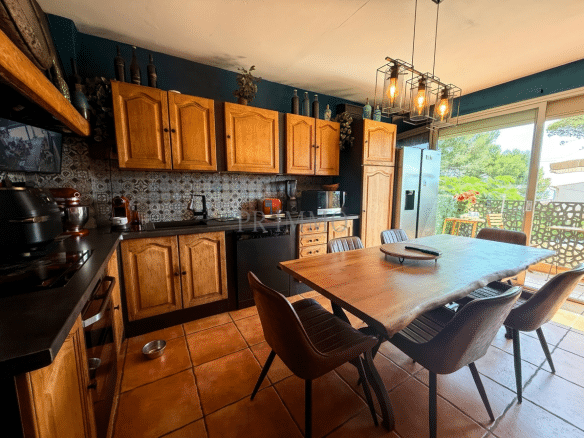 Kitchen with wooden furniture and dining table, overlooking a green balcony.