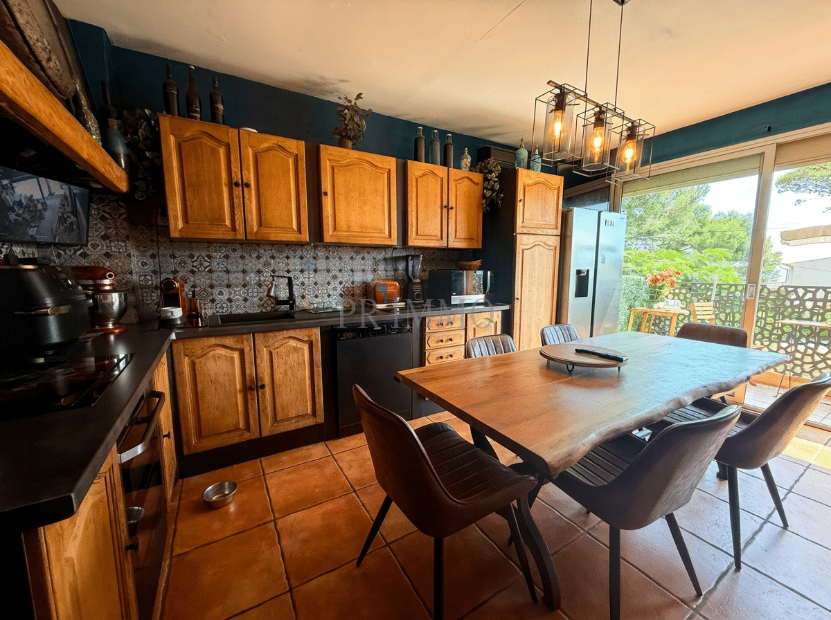 Spacious kitchen with balcony Kitchen with wooden furniture and dining table, overlooking a green balcony.