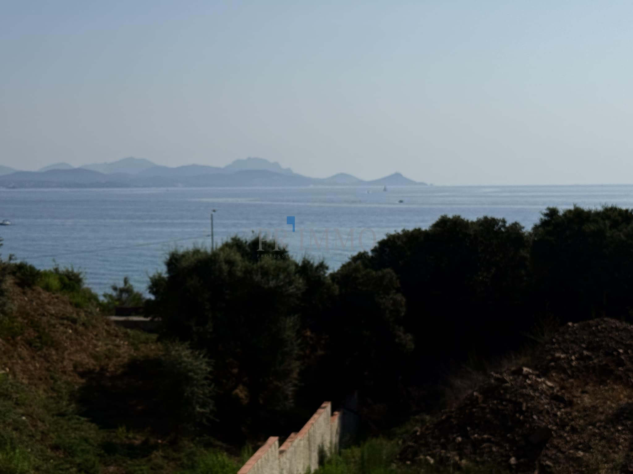 Vue sur la mer depuis un terrain à bâtir aux Issambres, avec des collines en arrière-plan.