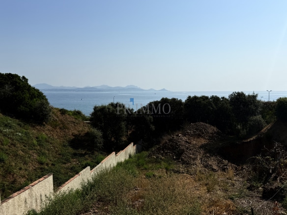 Terrain à bâtir avec vue sur la mer aux Issambres, entouré de végétation.