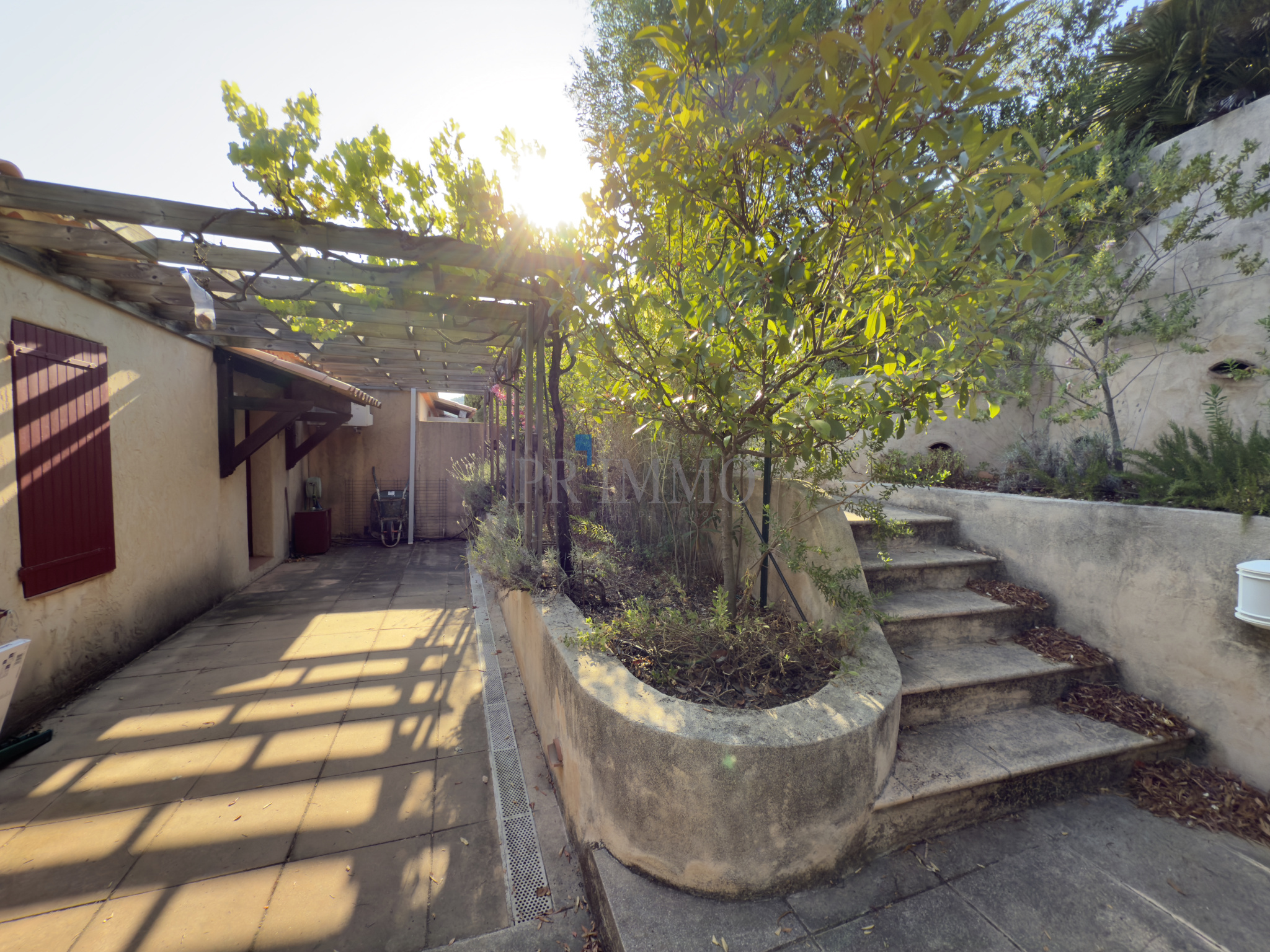 Jardin et terrasse d'une villa à Les Issambres avec lumière naturelle et végétation.