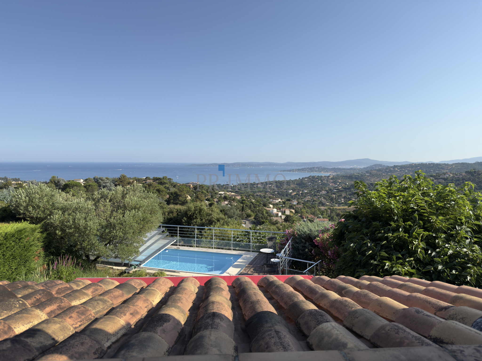 Vue panoramique sur le golfe de Saint-Tropez depuis une villa aux Issambres, avec piscine et verdure.