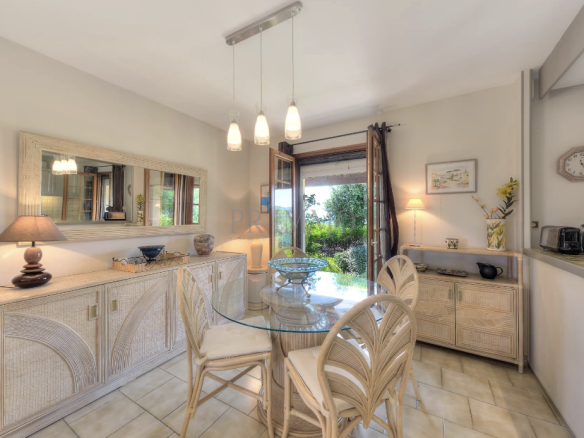 Bright dining room with glass table and wicker chairs, overlooking the garden.