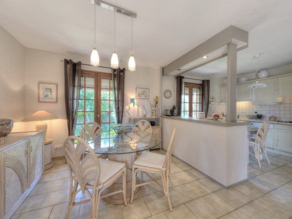 Interior of a single-storey villa with dining room and kitchen, abundant natural light.