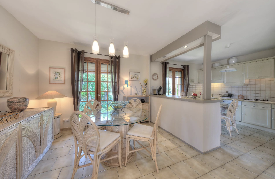 Interior of a single-storey villa with dining room and kitchen, abundant natural light.