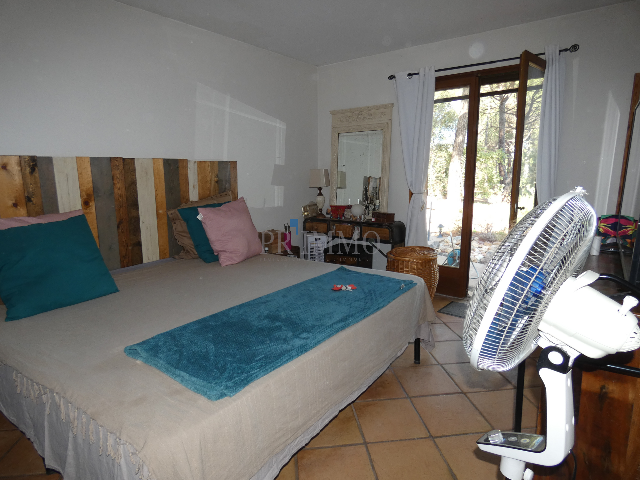 Chambre d'une villa avec lit, coussins colorés et accès à l'extérieur par une porte-fenêtre.
