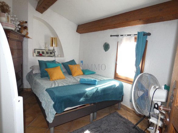 Chambre d'une villa avec lit double, oreillers colorés et ventilateur au plafond.