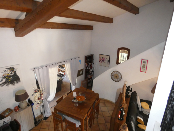 Intérieur d'une villa avec salle à manger en bois et cheminée, vue depuis le haut.