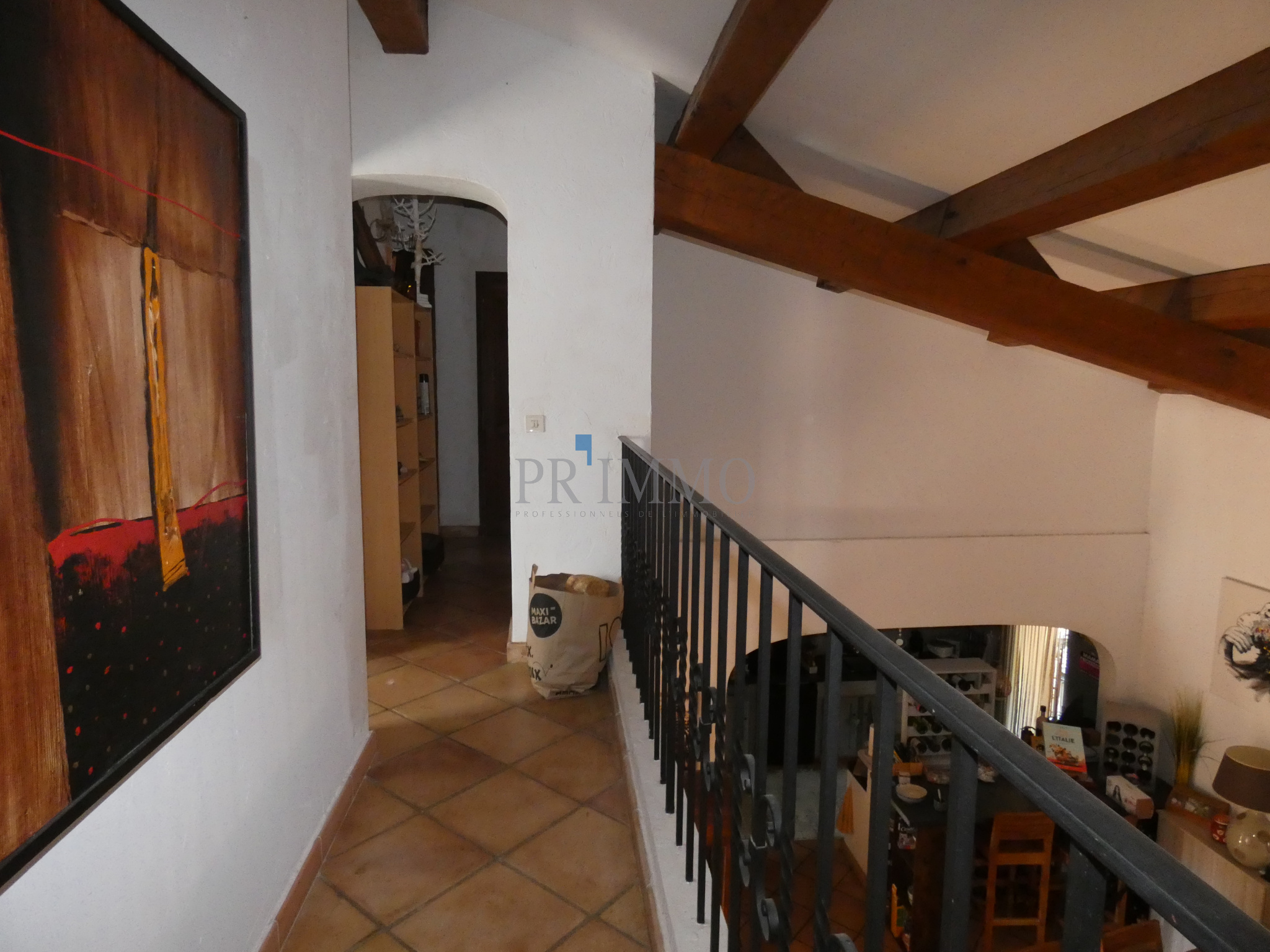 Intérieur d'une villa avec un couloir et des poutres apparentes.