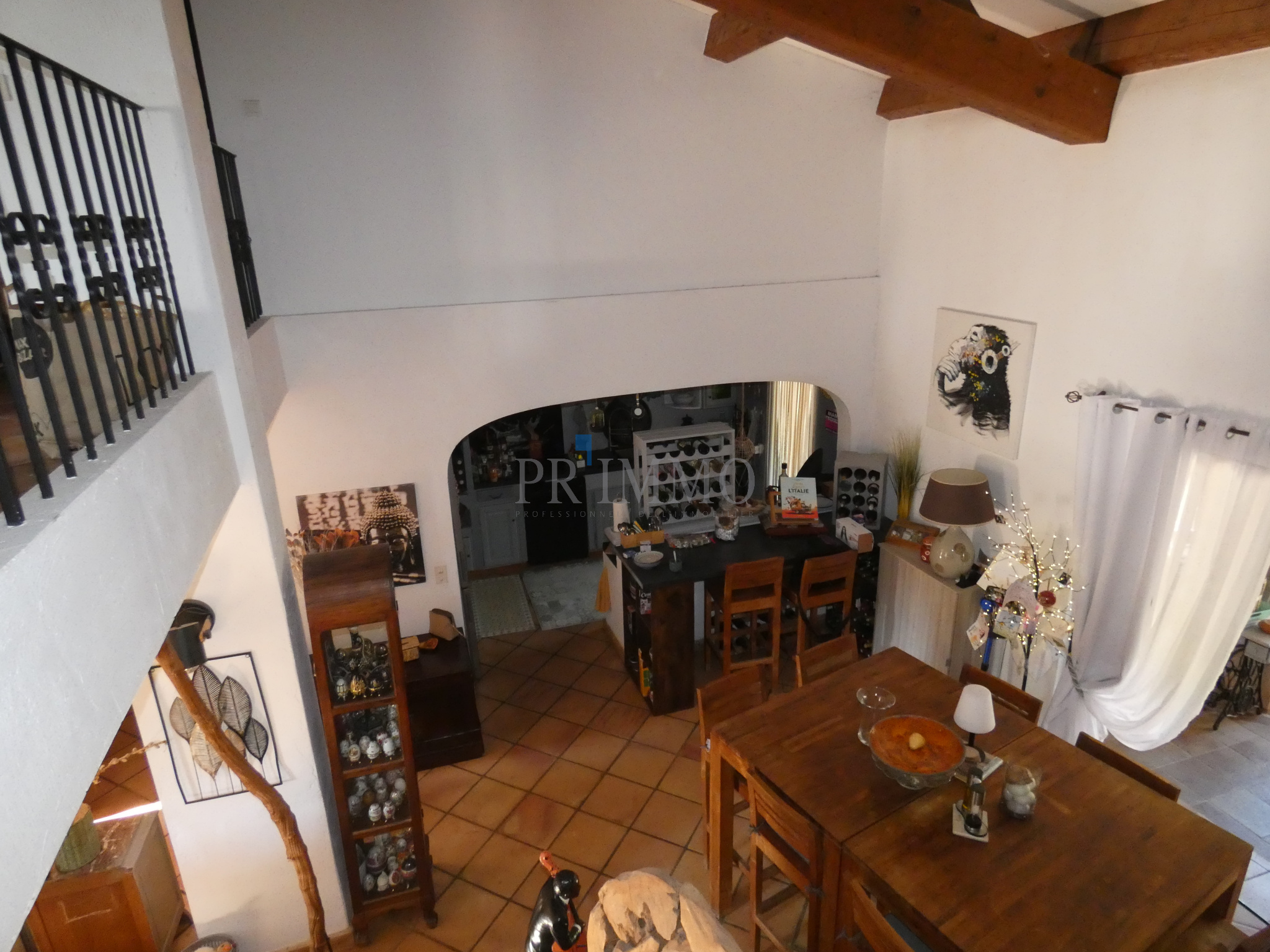 Intérieur d'une villa avec coin salon, cuisine ouverte et salle à manger, vue depuis l'étage.