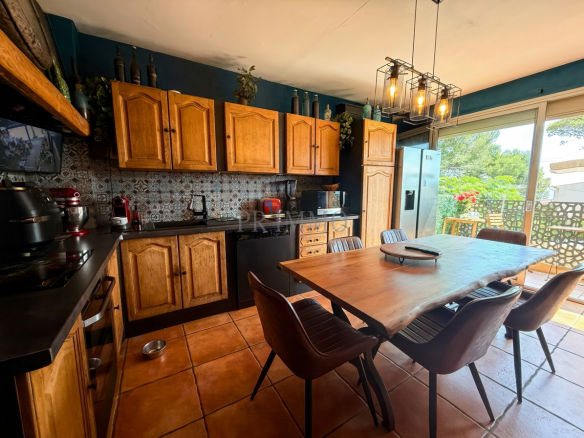 Cuisine moderne avec meubles en bois et table à manger, vue sur l'extérieur.