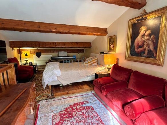 Intérieur d'une villa rénovée avec un salon confortable, un lit et des poutres apparentes.