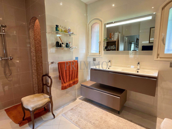 Salle de bain moderne avec douche, lavabo et miroir, décorée de carrelage clair.