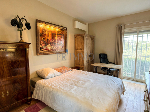 Chambre d'une villa rénovée avec lit, bureau et fenêtre donnant sur l'extérieur.