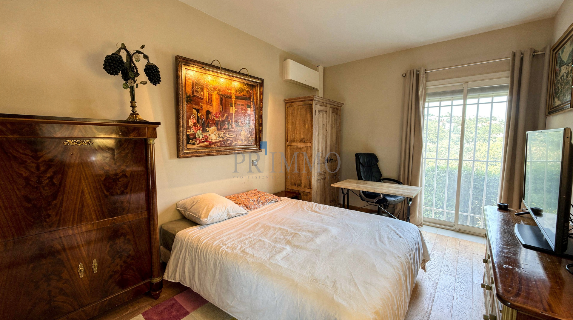 Chambre d'une villa rénovée avec lit, bureau et fenêtre donnant sur l'extérieur.