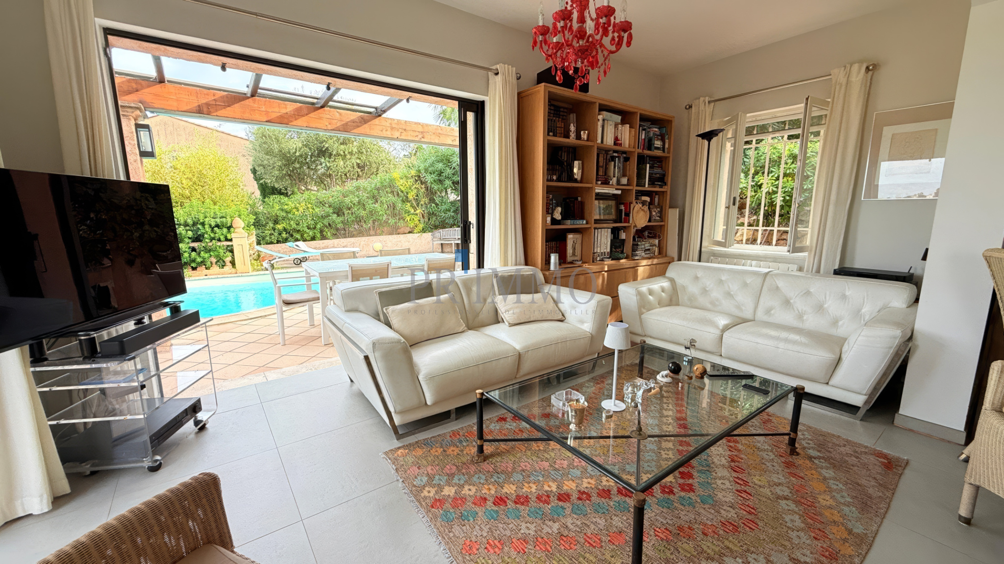 Intérieur d'une villa rénovée avec salon lumineux, vue sur la piscine et jardin.