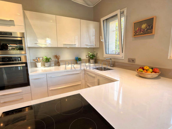 Cuisine moderne et lumineuse d'une villa rénovée, avec plans de travail en blanc et appareils intégrés.
