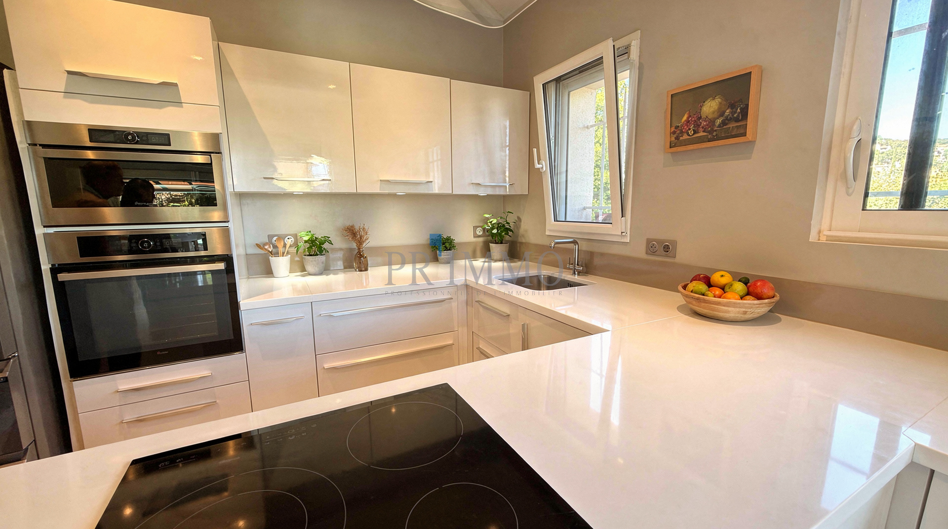 Cuisine moderne et lumineuse d'une villa rénovée, avec plans de travail en blanc et appareils intégrés.