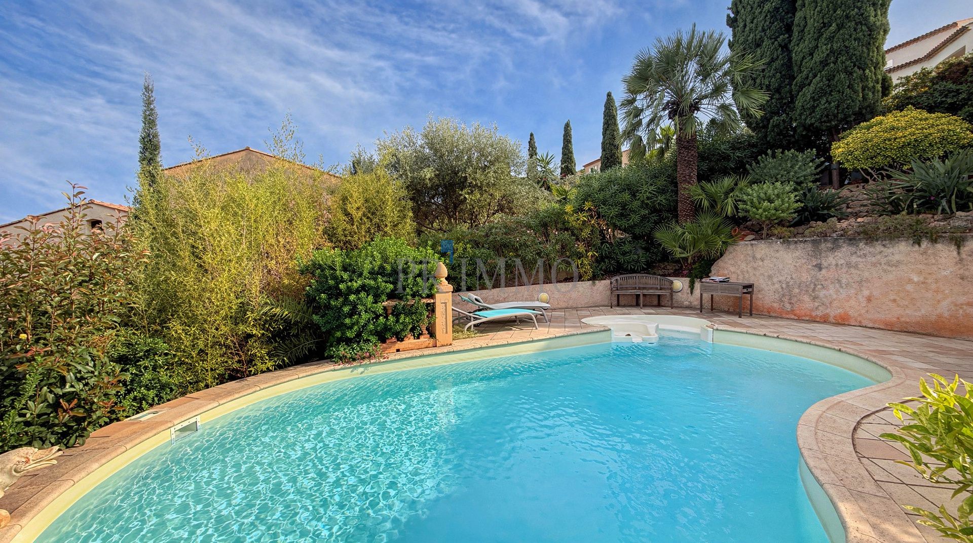 Piscine entourée de végétation dans une villa rénovée aux Issambres.