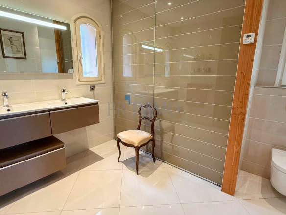 Salle de bain moderne avec double vasque et douche italienne dans une villa rénovée.