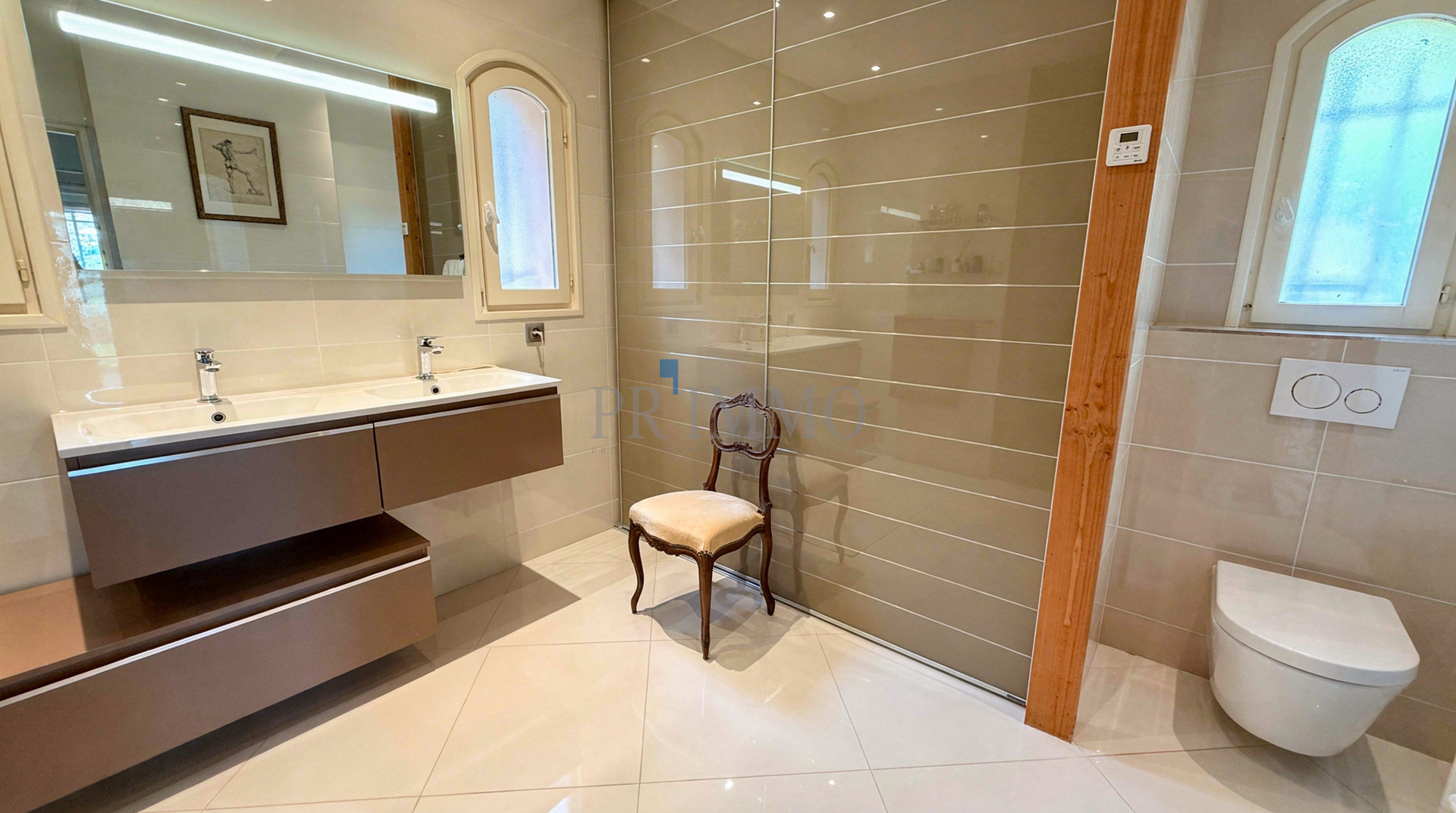 Salle de bain moderne avec double vasque et douche italienne dans une villa rénovée.