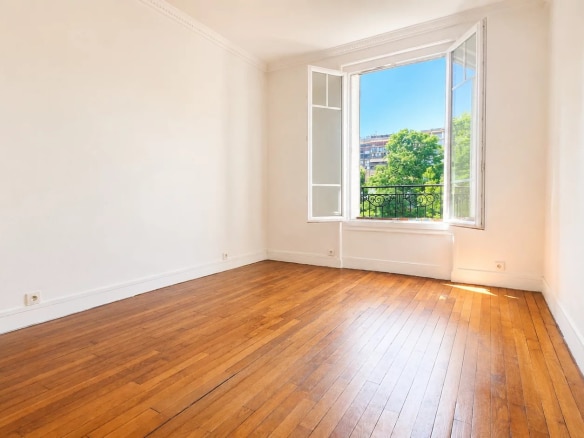 Interior of a renovated apartment in Meudon with parquet flooring and windows opening to the outside.