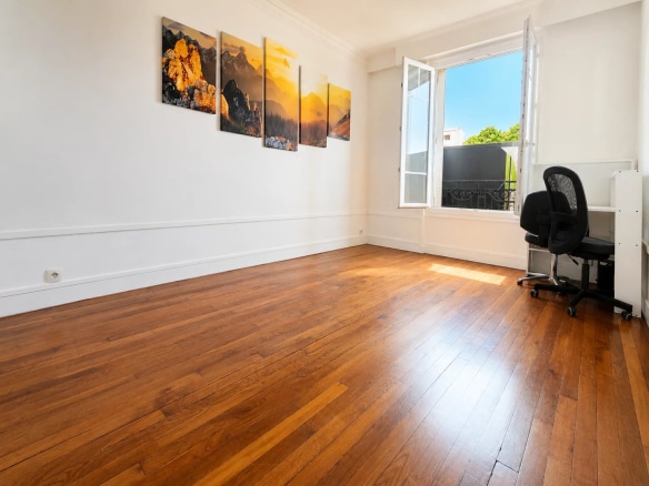 Interior of a renovated apartment with parquet flooring, open windows and a desk, in Meudon.