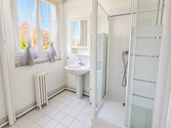 Modern bathroom with shower and sink, windows letting in natural light.